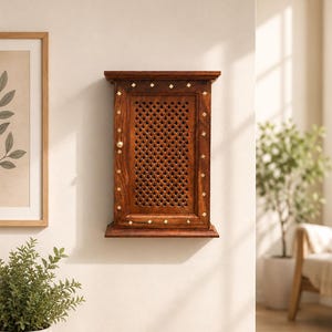 Puede incluir: Un mueble de madera montado en la pared con una puerta de celosía. El mueble es de color marrón cálido, adornado con pequeños acentos cuadrados de color dorado. Un pequeño pomo de latón sirve como tirador de la puerta. Está montado en una pared color crema.