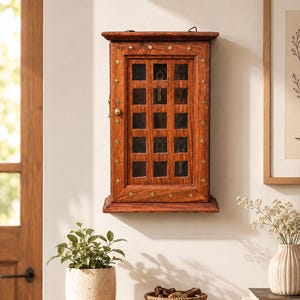 Könnte beinhalten: Ein rechteckiger, wandmontierter Schlüsselschrank aus Holz mit dunkelbrauner Oberfläche. Der Schrank verfügt über eine verglaste Tür mit Gittermuster, einen kleinen Messingknopf und dekorative rautenförmige Messingeinlagen am Rahmen.