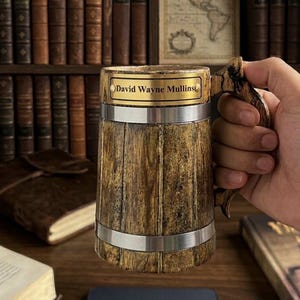 K&ouml;nnte beinhalten: Ein zylindrischer Bierkrug aus Holz mit einer strukturierten, dunkelbraunen Holzmaserung, zwei horizontalen silberfarbenen Metallb&auml;ndern und einem geschwungenen Griff. Oben ist eine rechteckige goldfarbene Metallplakette mit der Gravur David Wayne Mullins angebracht.