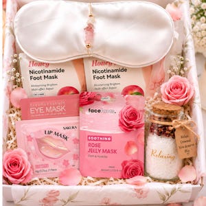 May include: A gift box containing a white satin sleep mask with a beaded chain, two Honey Nicotinamide Foot Mask packets, a Sakura Essence Eye Mask, a Sakura Lip Mask, a Face Facts Rose Jelly Mask, and a glass jar of bath salts with a cork lid.