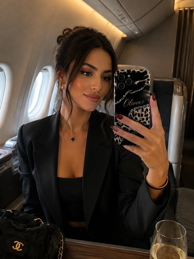 May include: A black smartphone case featuring a leopard print pattern, a black section with silver glitter accents, and the name Olivia written in cursive script. The case has a triple camera cutout and a glossy finish, designed for a mobile device.