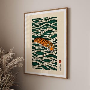 May include: Framed art print featuring a tiger swimming in stylized green and white waves. The tiger has orange and black stripes with a white face. The artwork is in a rectangular format with a beige background and a wooden frame.