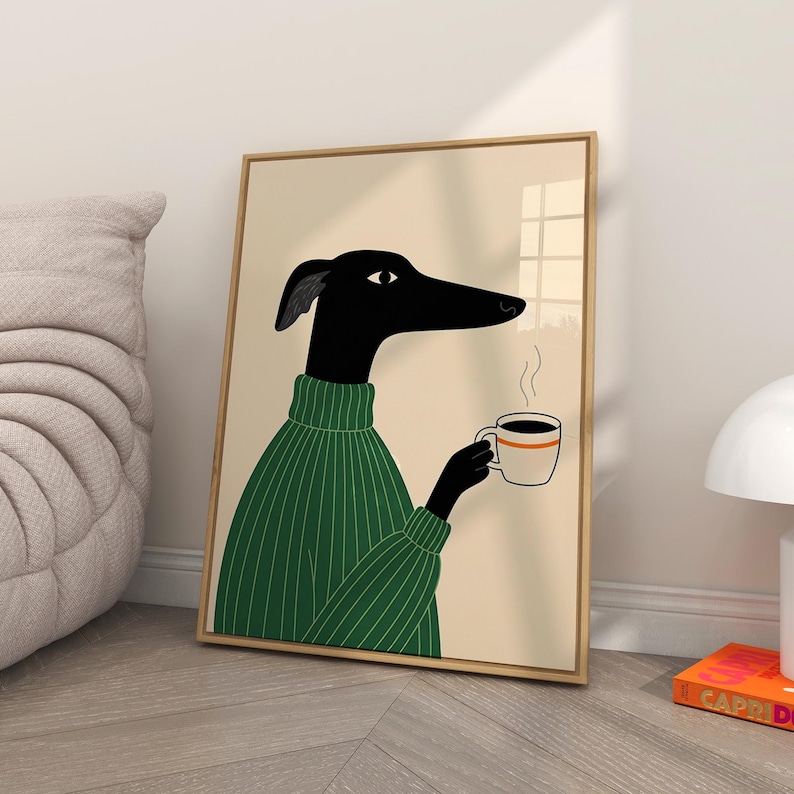 May include: A framed art print depicting a black dog-like character in a green sweater, holding a coffee cup with steam rising. The illustration is minimalist, set against a beige backdrop, and framed in wood. A quirky piece of art for home decor.