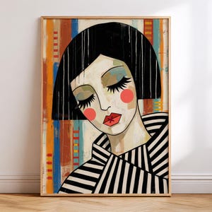 May include: A framed wall art print featuring a stylized portrait of a person with a black bob haircut, closed eyes, and long lashes. The figure wears a black and white striped garment against a background of vertical orange, blue, and red lines.