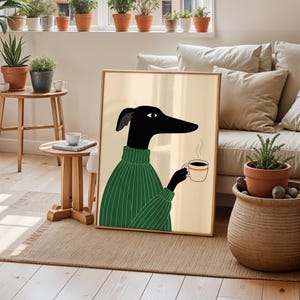 May include: Framed art print depicting a black dog in a green sweater, holding a coffee cup with steam rising. The dog has a long snout and a single eye. The background is a light beige, and the frame is light brown.