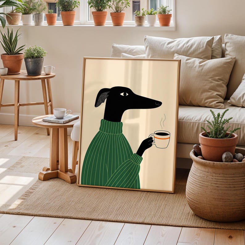 May include: Framed art print depicting a black dog in a green sweater, holding a coffee cup with steam rising. The dog has a long snout and a single eye. The background is a light beige, and the frame is light brown.