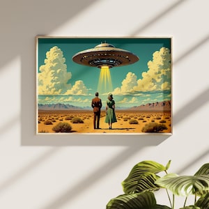May include: A framed art print depicts a retro-style scene of a couple standing in a desert landscape, gazing at a hovering UFO. The artwork features a teal sky, fluffy clouds, and a beam of light shining down from the spacecraft.