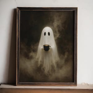 May include: A framed wall art print featuring a white ghost figure emerging from dark, swirling smoke. The ghost has two black oval eyes and is holding a small, dark-coloured mug filled with a light-coloured beverage in its centre.