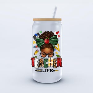 May include: A white glass tumbler with a wooden lid and a straw. The tumbler features a graphic of a teacher with glasses, a green bow, and the words "TEACHER LIFE" in colorful letters. The design includes school-related elements.