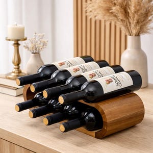Peut inclure: Un casier à vin en bois contenant plusieurs bouteilles de vin rouge. Le casier est en bois brun clair et présente un design incurvé. Les bouteilles de vin sont sombres avec des étiquettes blanches. Une bougie et un vase sont en arrière-plan.