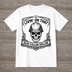 May include: White t-shirt featuring a black and white graphic. The graphic includes a skull wearing a hard hat, surrounded by the text "LIVIN' ON THAT" and "BLUE COLLAR DOLLAR" in a decorative frame.