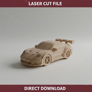 Peut inclure: Une voiture de course jouet en bois avec un aileron et des roues détaillées. La voiture est en bois clair et porte les textes "LASER CUT FILE" et "DIRECT DOWNLOAD".