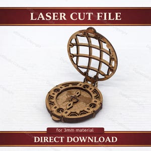 Puede incluir: Un diseño de brújula de madera cortada con láser con una parte superior en forma de globo, con el texto "LASER CUT FILE" y "DIRECT DOWNLOAD". La brújula tiene detalles intrincados y está diseñada para material de 3 mm.