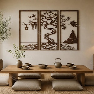May include: A triptych of dark wood wall art panels featuring laser-cut designs of a hanging lantern, a central tree, and a seated figure. Below, a low wooden table holds a ceramic teapot and bowls, surrounded by four beige floor cushions.