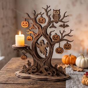 May include: A dark brown laser-cut wooden tree sculpture featuring a candle holder on the left side with a lit white pillar candle. The tree is decorated with hanging jack-o'-lanterns, bats, an owl, a ghost in the centre, and snakes at the base.