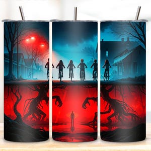 Pode incluir: Conjunto de três canecas de aço inoxidável com um design envolvente com uma cena de uma popular série de ficção científica. O design mostra crianças em bicicletas, um submundo vermelho e a silhueta de uma pessoa.