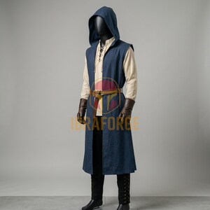 K&ouml;nnte beinhalten: Eine &auml;rmellose, dunkelblaue Kaputzentunika &uuml;ber einem beigen Langarmhemd mit Schn&uuml;rung am Ausschnitt. Das Outfit umfasst einen braunen Lederg&uuml;rtel, dunkelbraune Lederhandschuhe und eine schwarze Hose. Der Text IBRAFORGE ist in Orange zu sehen.