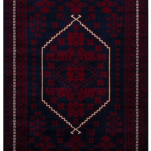 May include: A rectangular, dark blue rug with a central geometric design in deep red. The rug features a white, zigzag border and intricate floral patterns. The edges are finished with a fringe.