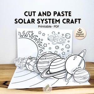 Puede incluir: Una manualidad del sistema solar imprimible en blanco y negro con el texto "Cut and Paste Solar System Craft". La manualidad incluye dibujos lineales del sol, los planetas, un cohete y estrellas. También son visibles las palabras "Printable PDF" y "Digital Download".