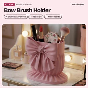 Puede incluir: Un porta brochas de color rosa mate con un gran lazo esculpido en la parte frontal y una base redondeada con pliegues. El recipiente contiene varios artículos de maquillaje, incluyendo una máscara, un labial rojo, un compacto y una brocha.