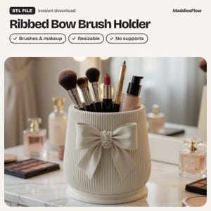 Puede incluir: Un portaescobillas cilíndrico de color crema con una textura acanalada vertical y un lazo decorativo prominente en la parte frontal. El soporte contiene varios pinceles de maquillaje, un pintalabios y un frasco con bomba. Texto: Ribbed Bow Brush Holder.