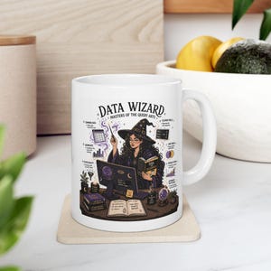 May include: White ceramic mug featuring a detailed illustration of a data wizard. The design includes a woman in a witch hat, a computer, books, and the text "DATA WIZARD MASTERS OF THE QUERY ARTS."