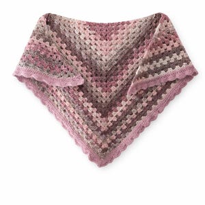 Op de afbeelding: Een handgemaakte driehoekige gehaakte sjaal. De sjaal heeft een granny stitch patroon in roze, mauve en grijstinten. De randen zijn afgewerkt met een geschulpte rand in donkerder roze.
