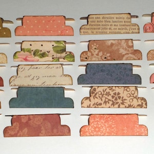 May include: A selection of decorative paper tabs in diverse colours and patterns. The tabs feature designs such as polka dots, floral prints, and vintage text. Each tab has a small metal attachment. Perfect for scrapbooking or crafting projects.