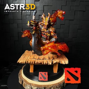 Puede incluir: Logotipo de ASTR3D. Figura detallada de un personaje con una espada, con acentos de color naranja y amarillo fuego. La figura se encuentra sobre una plataforma de madera con una base negra y dos cuadrados de logotipo rojos y negros.