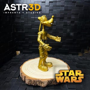 May include: A gold-coloured figurine of a hybrid character, combining the features of Goofy and C-3PO, stands on a wooden slice. The figurine is posed with one arm extended. The Star Wars logo is visible. The text "ASTR3D IMPRENTA Y STUDIOS" is at the top.