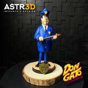 Puede incluir: Figura azul del Oficial Dibble de la serie "Don Gato", sosteniendo una porra marrón. La figura está sobre una base de madera con un escudo dorado que dice "Officer Dibble". El logo de "Don Gato" es visible.