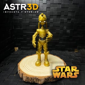 May include: A gold C-3PO figurine from Star Wars, displayed on a wooden slice. The figurine features intricate mechanical detailing. The Star Wars logo is visible. The text "ASTR3D IMPRENTA Y STUDIOS" is visible in the upper left corner.