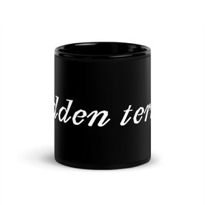 Puede incluir: Una taza de cerámica negra con las palabras "den ter" en escritura blanca. La taza es cilíndrica y parece estar vacía. El texto está centrado en la taza.