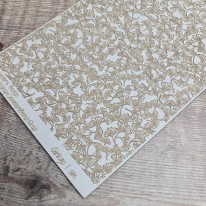 May include: A rectangular sheet with a repeating pattern of ginkgo leaves in a light brown color. The leaves are intricately detailed and cover the majority of the white surface. The text "Ginkgo | 1 SM" is visible in the lower right corner.