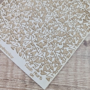 May include: A wooden craft panel with a repeating pattern of carved hearts. The hearts are in various sizes and orientations, creating a textured surface. The words "Doodle Hearts" and "sm" are visible in the corner.