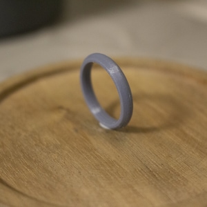 Può includere: Un anello di plastica grigia con una superficie liscia e arrotondata.