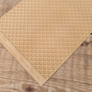 Puede incluir: Una hoja texturizada de color beige claro con un patrón repetido de azulejos marroquíes. La hoja está en ángulo, revelando una esquina y las palabras "Moroccan Tiles | SM" y otro texto en el borde.