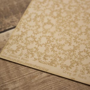 May include: A rectangular beige sheet featuring a repeating tan vine and leaf pattern. The text "The Jeweler's Bench www.etsy.com/shop/JewellersBenchShop" and "String of Pearls" is printed in the bottom corner of the sheet.
