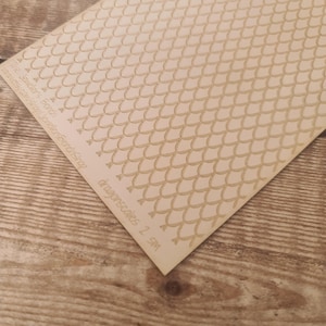 May include: A sheet of paper featuring a repeating pattern of light brown dragon scales. The text "dragonscales 2 SM" is printed in the lower right corner. Additional text is printed in the upper left corner.