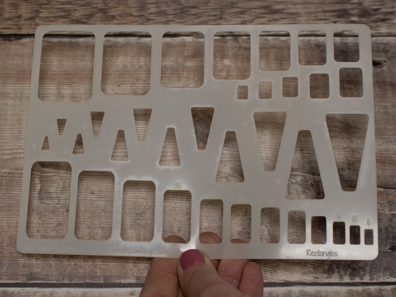 May include: A clear plastic stencil with various shapes, including triangles and rectangles. The stencil is labeled "Rectangles" and has measurements in inches.