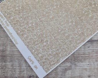 May include: A rectangular sheet featuring a repeating pattern of small, light beige swirls on a white background. The left margin contains printed text that reads Jewelers Bench and Swirls SM in a light beige color, oriented vertically.