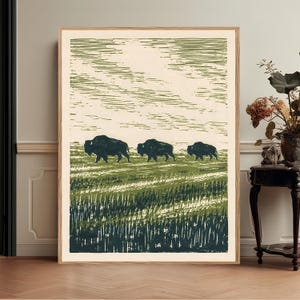 Può includere: Una stampa artistica incorniciata che presenta un'illustrazione in stile xilografia con tre bisonti verde scuro che camminano attraverso un campo erboso. Lo sfondo è composto da linee orizzontali in tonalità verde chiaro e crema.