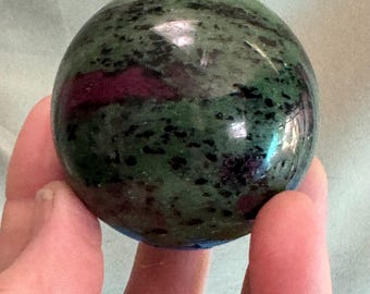 Rubí en esfera de zoisita verde / Rubí rojo brillante bajo luz ultravioleta: pasión y transformación alegre