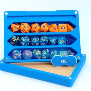 May include: A blue dice case with three compartments, each holding a set of polyhedral dice in various colors. The top row has orange dice, the middle row has blue dice, and the bottom row has purple and teal dice. A small counter shows the number 10.