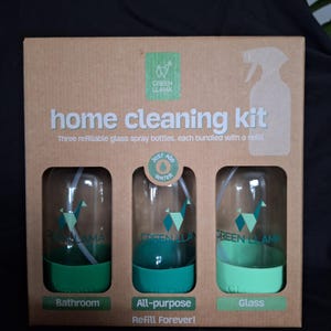 May include: A home cleaning kit containing three refillable glass spray bottles. Each bottle has a green base and a spray nozzle. The kit includes bottles labelled "Bathroom", "All-purpose", and "Glass". The box is made of cardboard and features the "Green Llama" logo.