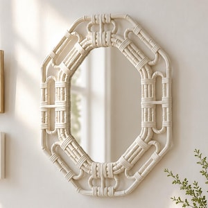 May include: An octagonal wall mirror featuring a cream-colored frame constructed from woven rattan reeds. The frame displays a geometric pattern with vertical segments and looped corners, surrounding a central reflective glass pane.