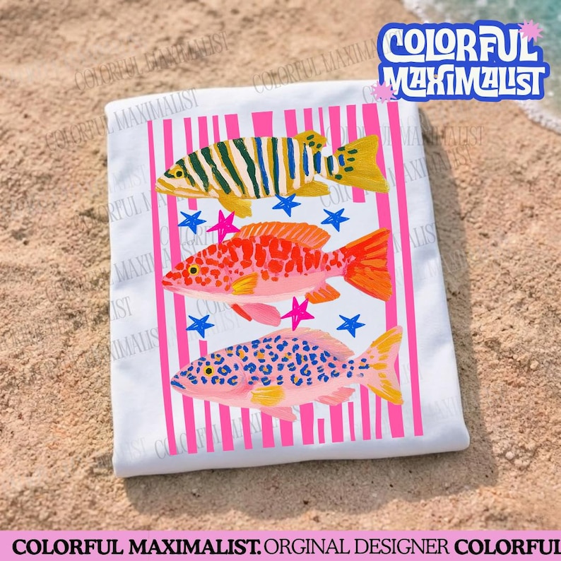 May include: White beach towel featuring three colorful fish illustrations with pink vertical stripes and blue and pink star accents. The towel has the text "COLORFUL MAXIMALIST" in a blue and white font.