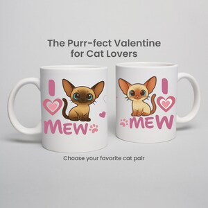 May include: Two white ceramic mugs with cat illustrations. One mug features a brown cat with blue eyes, a pink heart, and the word "MEW." The other mug has a light brown cat, a pink heart, and the word "MEW." Text above reads "The Purr-fect Valentine for Cat Lovers."