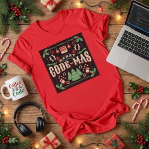 May include: A red t-shirt with a festive "MERRY CODE-MAS" design, featuring coding symbols and Christmas tree graphics. A white mug with "Coffee & Code" text is visible. The scene includes a laptop, headphones, and holiday decorations.