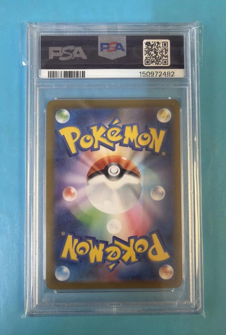 May include: A graded Pok&eacute;mon trading card encased in a clear plastic holder. The card back features the Pok&eacute;mon logo and a Pok&eacute; Ball design. The holder has a PSA label and a serial number.